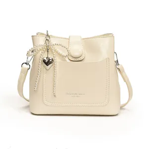 Sac seau minimaliste crème avec nœud en perles et pendentif cœur argenté, vue face