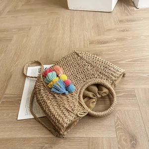 Detail of hand-woven straw bag featuring colorful tassels and round rigid handles