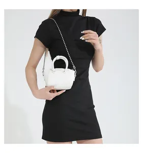 Detailed view of white mini crossbody bag with silver ball chain strap on model
