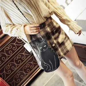 Petit sac à bandoulière chat noir avec chaîne en métal porté par un mannequin en intérieur