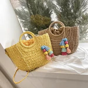 Close-up of bohemian woven straw bag featuring colorful tassel charms and drawstring liner