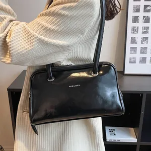 Classic black glossy underarm bag with silver logo in a stylish lifestyle setting