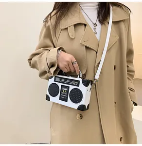 Detail of retro boombox shaped handbag with silver metal handle and white shoulder strap