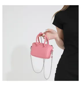 Detailed shot of pink mini leather bag featuring silver beaded chain and top handles