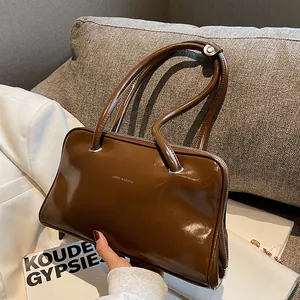 Brown patent leather shoulder bag with silver logo in a stylish casual interior setting
