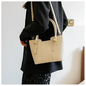Close-up of cream lychee grain leather handbag with gold hardware and dual handles