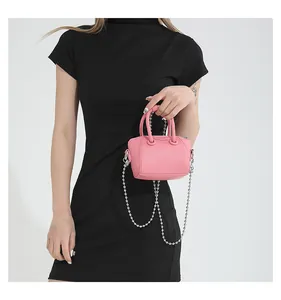 Close-up of pink mini handbag with metallic bead chain strap worn by a model