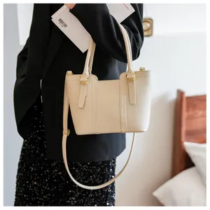 Detail of beige pebbled leather texture and gold-tone metal hardware on the handbag