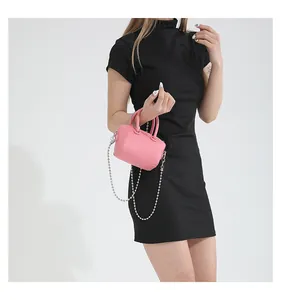 Pink mini crossbody pillow bag with silver chain strap shown on a black dress