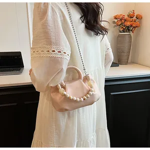 Détail d'un sac plissé rose avec poignée en perles marbrées et fine bandoulière chaîne