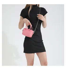 Detailed view of pink leather mini Boston bag with silver chain strap on black dress