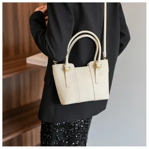 Detail of cream pebbled leather tote bag with gold buckles and dual top handles