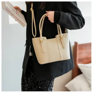 Detail shot of beige lychee texture leather handbag with light gold hardware and stitching