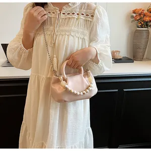 Détail du sac nuage rose clair avec texture plissée et poignée décorative en perles