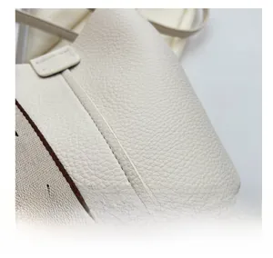 Gros plan du sac seau en cuir grainé blanc cassé avec surpiqûres et bandoulière chic