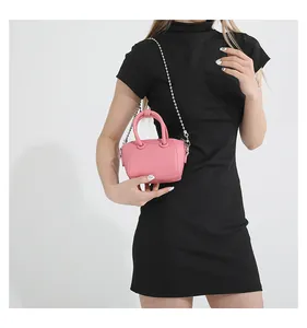 Detail of pink mini leather crossbody bag featuring silver chain strap and top handles