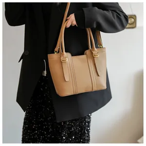 Close-up of khaki lychee grain leather tote bag with gold ring hardware and vertical stitching