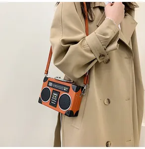Detailed view of creative vintage radio shaped crossbody bag styled with a khaki coat