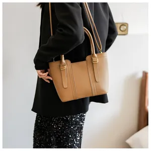 Detail view of a tan pebble leather tote bag with vintage gold hardware and dual handles