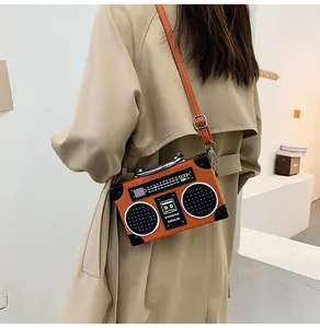Detail view of a bright orange vintage radio bag worn on a beige trench coat