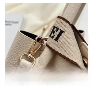 Détails des crochets dorés et du cuir grainé sur le sac seau de couleur crème