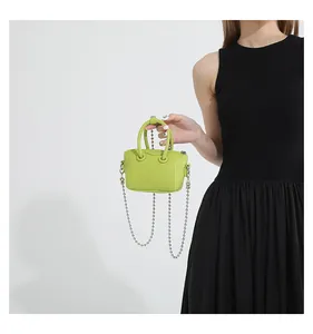 Detail of neon green mini bag with silver chain strap on a black dress backdrop