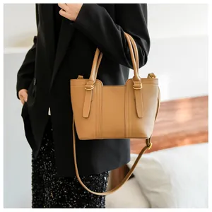 Close-up of camel leather bucket bag with gold buckles and adjustable shoulder strap