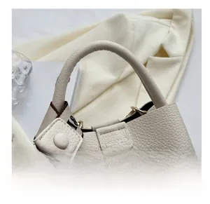 Détail du sac seau crème en cuir grainé avec une bandoulière tissée élégante