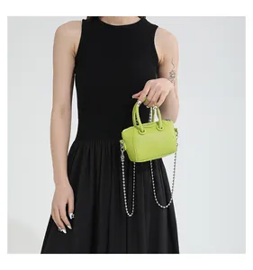 Detailed view of neon green mini leather bag with silver ball chain on a model
