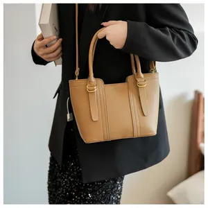 Detail of camel brown leather bucket bag with gold hardware and adjustable strap