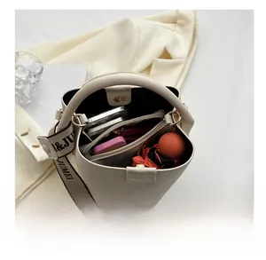 Vue de dessus d'un sac seau crème montrant l'intérieur spacieux avec téléphone et objets
