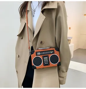 Detail of creative vintage radio shaped crossbody bag in orange on a khaki trench coat