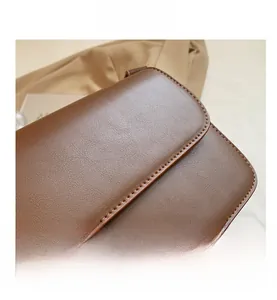Primer plano detallado de la textura del cuero marrón y las costuras de un bolso cuadrado chic