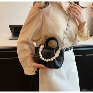 Détail du sac nuage en cuir noir avec poignée perlée et chaîne en métal sur modèle
