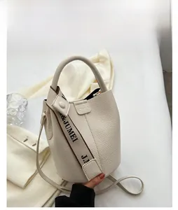 Vue détaillée du sac seau crème montrant la texture grainée et la bandoulière large