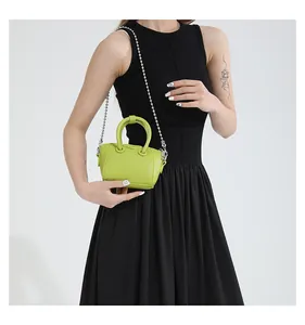 Detail of neon green mini crossbody bag with litchi leather texture and bead chain