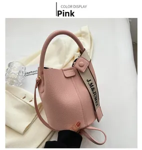 Sac seau rose avec cuir à texture litchi et bandoulière tissée large à lettres élégante