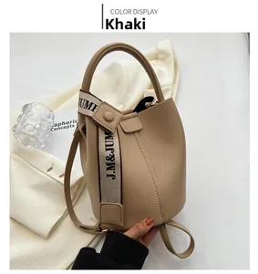 Détails du sac seau kaki en cuir grainé avec bandoulière en toile à lettres