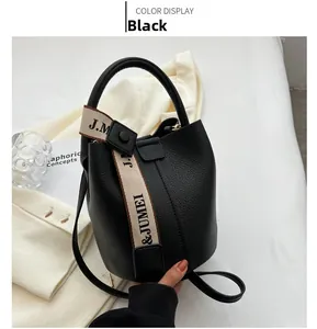 Détail du sac seau noir grainé avec sangle logo J.M & JUMEI et texture en cuir luxueux
