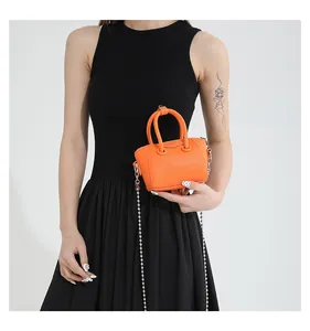 Close-up of mini orange lychee pattern leather handbag with silver ball chain strap