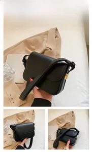 Detalle de bolso bandolera de cuero negro con hebilla dorada y correa de nudo artístico