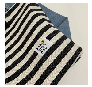 Detailed macro view of the striped canvas texture and the smiley face emblem on the tote bag