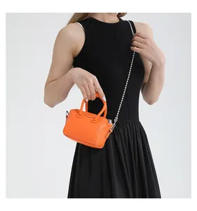 Close-up of bright orange micro bag featuring litchi grain texture and silver bead chain