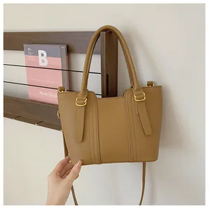Close-up of brown litchi pattern leather tote bag with gold metal hardware and stitching