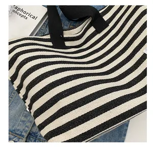 Detail of canvas tote bag with black and white stripes on blue denim jacket