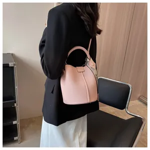 Détail du sac seau en cuir litchi rose avec une large bandoulière imprimée tendance