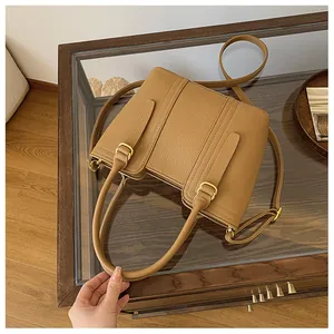 Detailed macro view of the double top handles and golden hardware on a brown bucket bag
