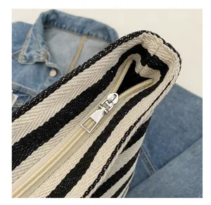 Detail shot of smooth silver metal zipper on black and white striped canvas tote bag