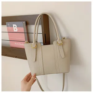 Detail of beige lychee grain leather bucket bag with gold hardware and vertical stitching