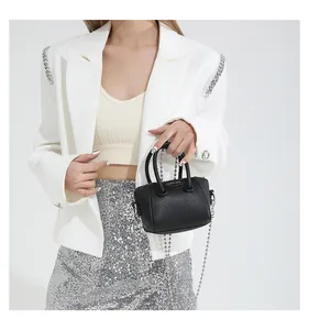 Close-up of mini black lychee leather handbag with silver bead chain strap on model
